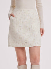 A lady wears a white tweed mini skirt.